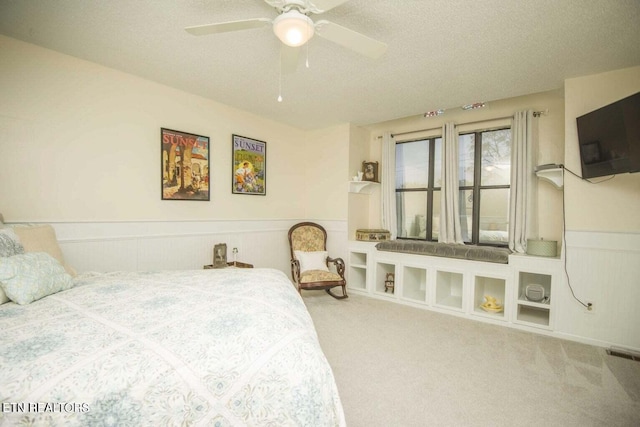 bedroom with visible vents, wainscoting, a textured ceiling, and carpet