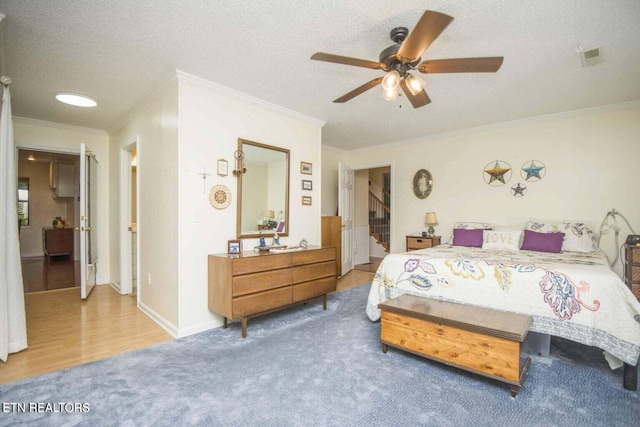 bedroom featuring a ceiling fan, wood finished floors, baseboards, ornamental molding, and a textured ceiling