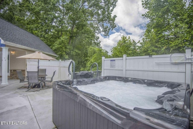 view of patio / terrace with a hot tub, outdoor dining area, and fence