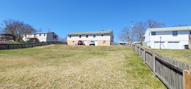 view of yard with an attached garage and a fenced backyard