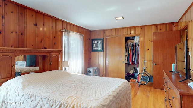 bedroom featuring a closet, wooden walls, and light wood-style flooring