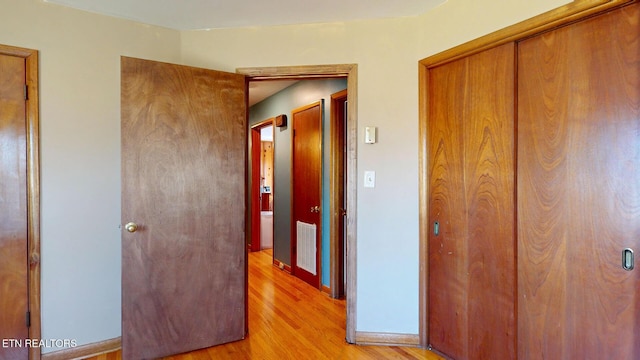 corridor featuring light wood-type flooring, baseboards, and visible vents