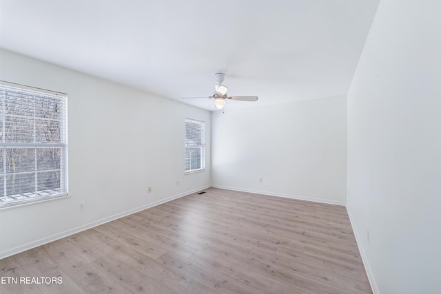 spare room with baseboards, light wood-style floors, and ceiling fan