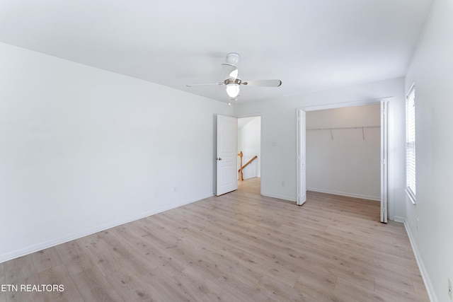 unfurnished bedroom with a closet, ceiling fan, light wood-type flooring, and baseboards