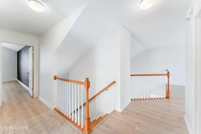 hallway with baseboards, an upstairs landing, and wood finished floors