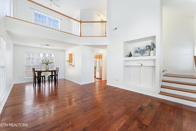 dining area featuring baseboards, built in features, stairway, a towering ceiling, and hardwood / wood-style flooring