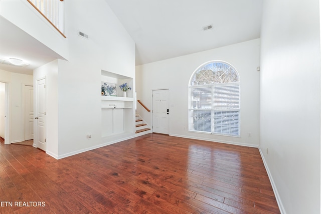 interior space featuring stairway, baseboards, dark wood-type flooring, and visible vents