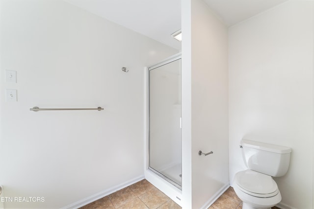 bathroom with tile patterned floors, a shower stall, toilet, and baseboards