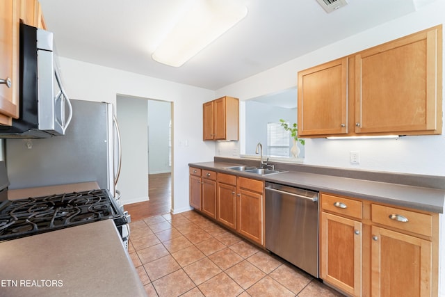 kitchen featuring light tile patterned floors, baseboards, visible vents, a sink, and appliances with stainless steel finishes