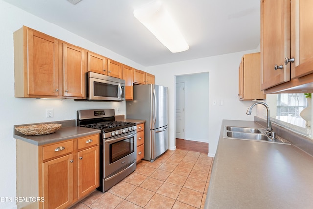 kitchen with light tile patterned floors, stainless steel appliances, baseboards, and a sink