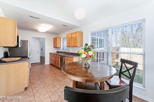 kitchen with light tile patterned floors, visible vents, lofted ceiling, light brown cabinetry, and appliances with stainless steel finishes