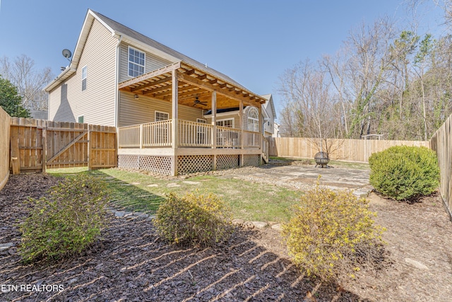 rear view of property with a deck, a gate, a fenced backyard, and a ceiling fan