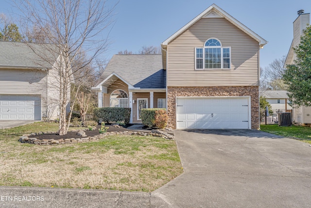 traditional home featuring central air condition unit, an attached garage, concrete driveway, and a front yard