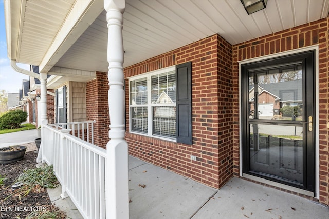 property entrance featuring a porch and brick siding