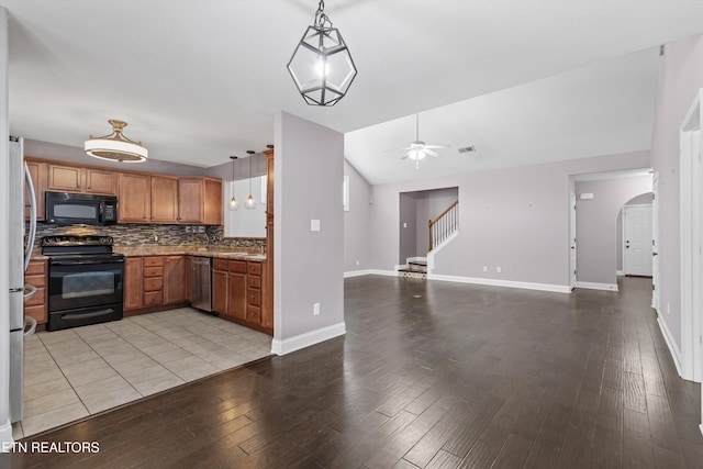 kitchen featuring arched walkways, ceiling fan, black appliances, open floor plan, and tasteful backsplash
