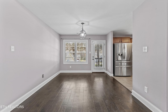 unfurnished dining area featuring dark wood-style floors and baseboards
