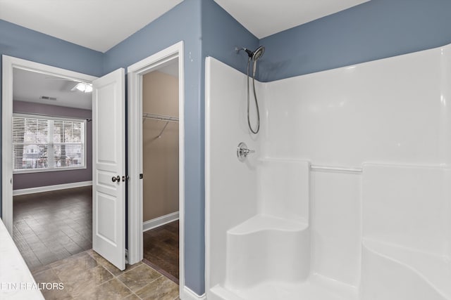 bathroom with a shower, visible vents, baseboards, and a walk in closet