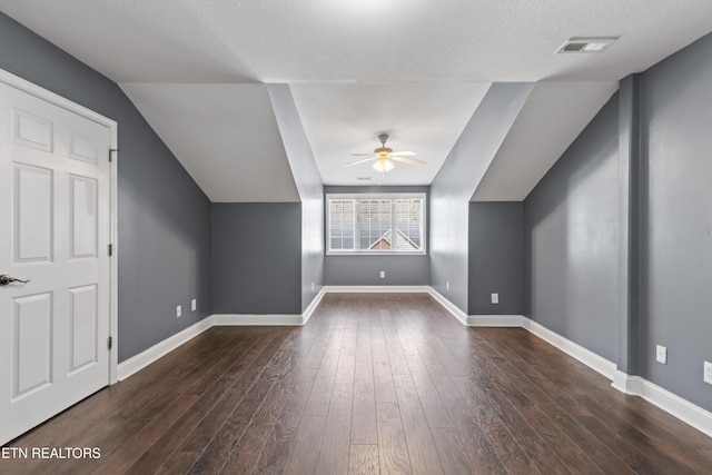 additional living space with visible vents, baseboards, lofted ceiling, a ceiling fan, and dark wood-style flooring