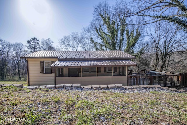 back of house with metal roof and a wooden deck