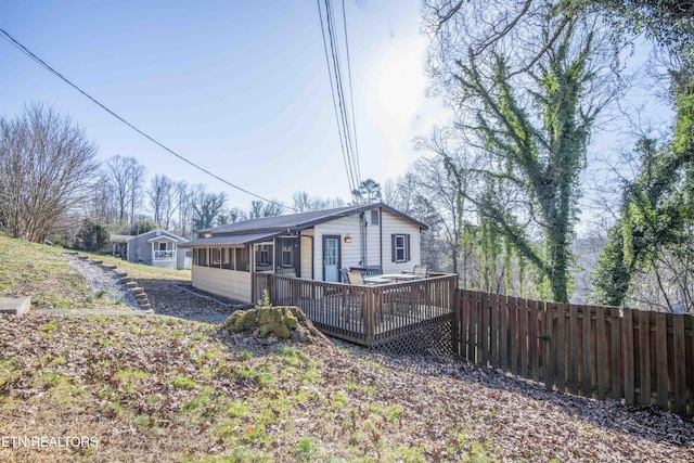 exterior space featuring a wooden deck, a sunroom, and fence