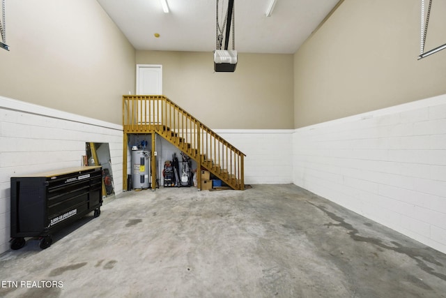 garage featuring water heater, a wainscoted wall, and a garage door opener