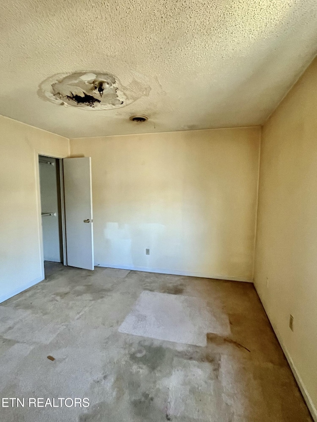 unfurnished room featuring unfinished concrete floors and a textured ceiling