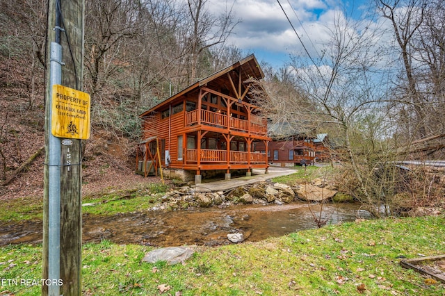 back of house with faux log siding and a wooden deck