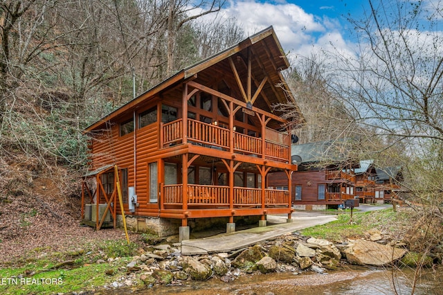 back of property with a balcony and log veneer siding