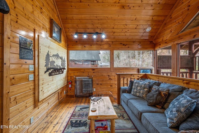 living area featuring hardwood / wood-style floors, lofted ceiling, wooden walls, and wooden ceiling