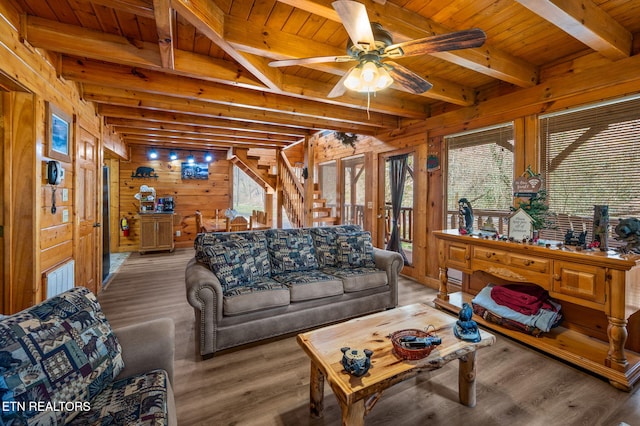 living room featuring beam ceiling, stairs, wood walls, wooden ceiling, and light wood-type flooring