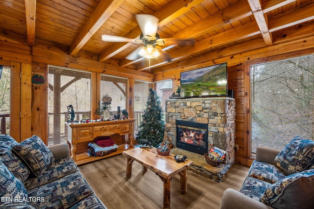 living area with wooden walls, wood finished floors, beam ceiling, a fireplace, and wood ceiling