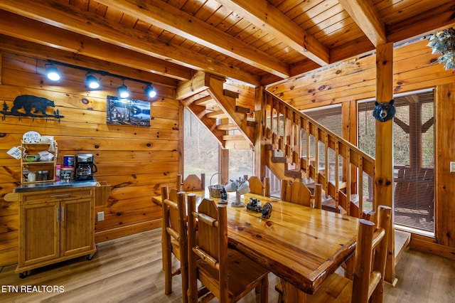 dining area featuring beam ceiling, wood walls, wood ceiling, and light wood-type flooring