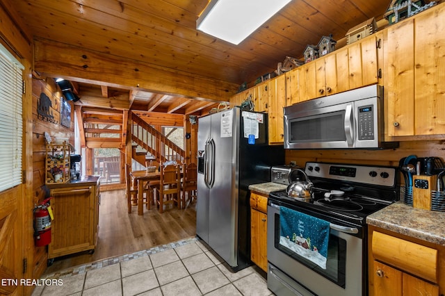 kitchen with light tile patterned floors, beam ceiling, appliances with stainless steel finishes, and wooden ceiling