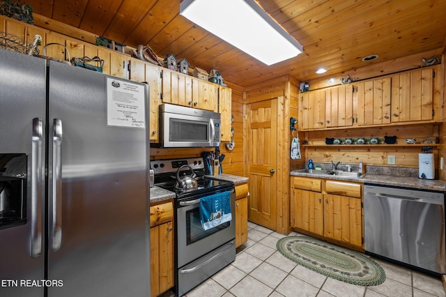 kitchen featuring wooden walls, light tile patterned floors, a sink, stainless steel appliances, and wood ceiling