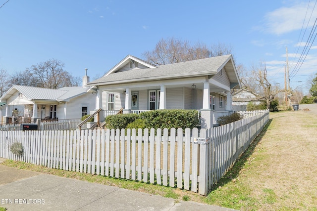 bungalow-style house featuring a fenced front yard, covered porch, and a shingled roof