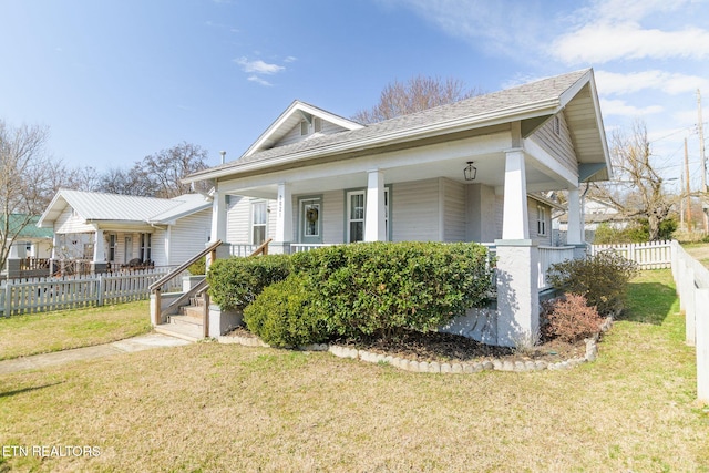 view of front of house featuring a front yard, a porch, fence, and roof with shingles