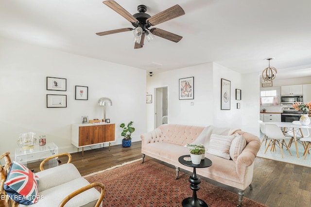 living room with ceiling fan with notable chandelier and dark wood-type flooring