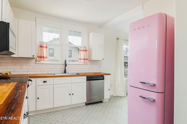 kitchen featuring a sink, stainless steel appliances, butcher block countertops, white cabinetry, and backsplash