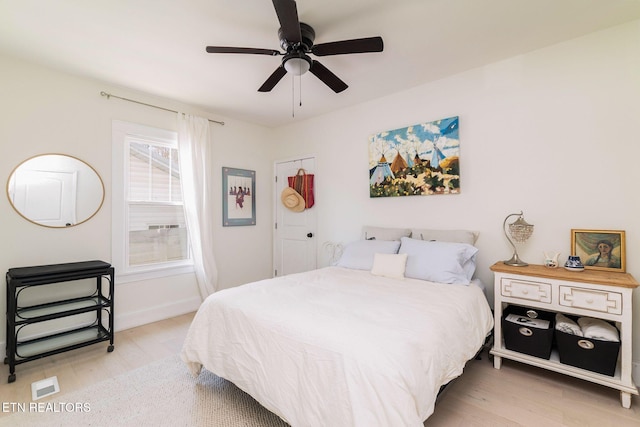 bedroom with ceiling fan, baseboards, and light wood-style floors