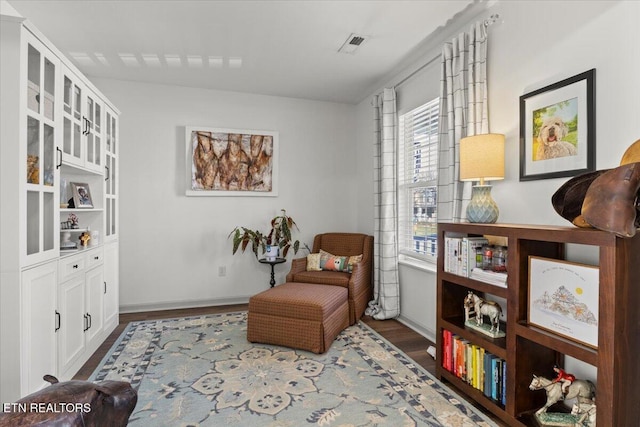 living area featuring wood finished floors, visible vents, and baseboards