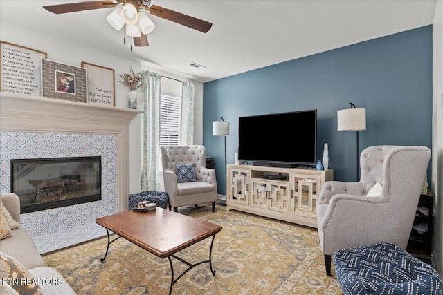 living room with a fireplace, visible vents, and ceiling fan