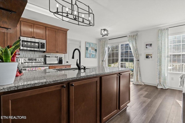 kitchen with a wealth of natural light, dark wood-style flooring, appliances with stainless steel finishes, and a sink