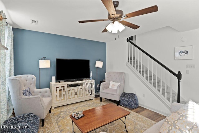 living room with visible vents, wood finished floors, a ceiling fan, and stairway