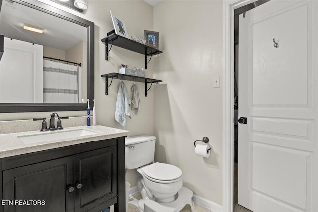 bathroom with baseboards, toilet, and vanity