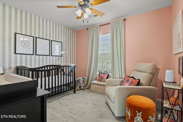 carpeted bedroom featuring wallpapered walls, a ceiling fan, visible vents, and an accent wall