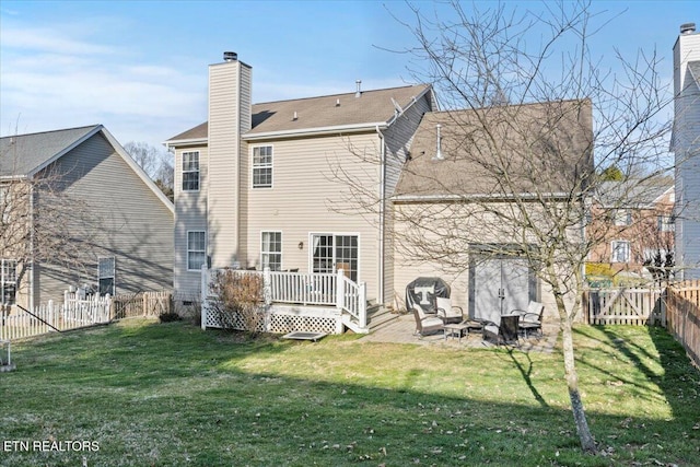 rear view of house featuring a yard, a fenced backyard, a chimney, and a wooden deck