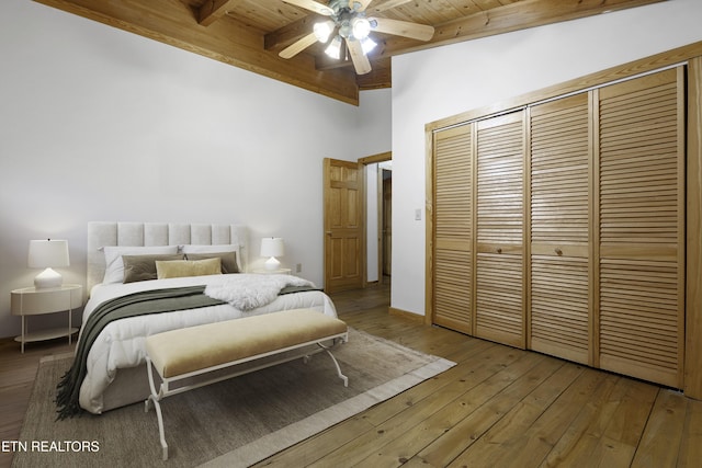 bedroom with beamed ceiling, hardwood / wood-style floors, wooden ceiling, a closet, and a ceiling fan