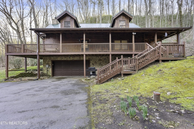 view of front of property featuring stairway, an attached garage, driveway, and metal roof