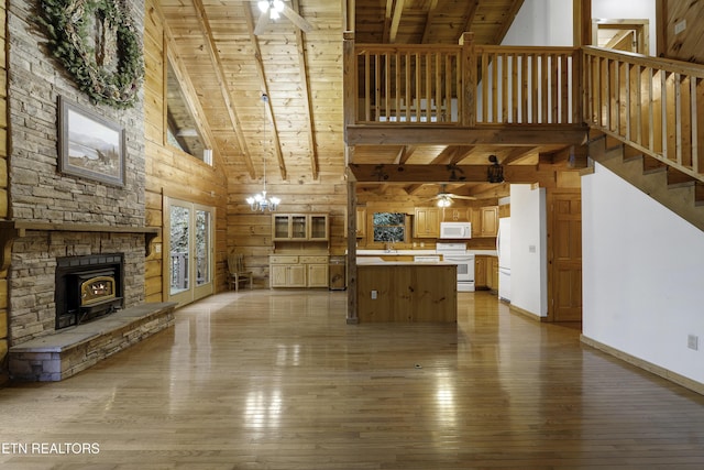 unfurnished living room with light wood finished floors, beamed ceiling, wooden ceiling, and a ceiling fan