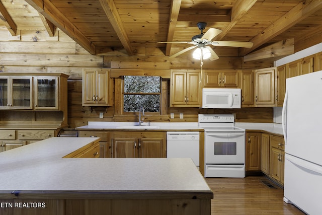 kitchen featuring white appliances, light countertops, wood walls, and a sink